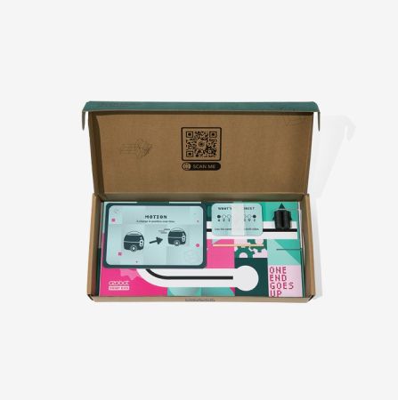 Open box view of the Ozobot OzoGoes Seesaw STEAM Kit, featuring illustrated instruction cards, colorful layout, and included seesaw component for STEM learning activities