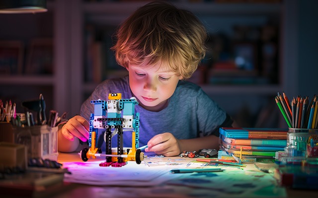 Child building a screen-free STEM toy robot at desk to support brain development and problem-solving skills